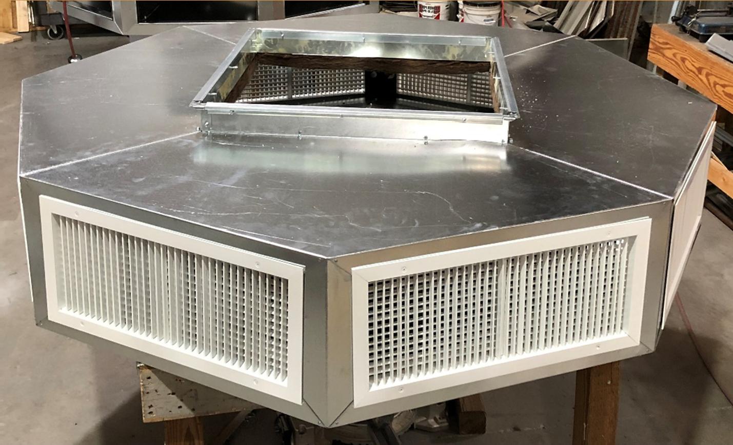 The EP Custom Double Deflection Drop Boxes - Six way, a large octagonal metal air ventilation unit with white grille vents and a square top opening, is installed indoors on a concrete floor as part of an air distribution system.