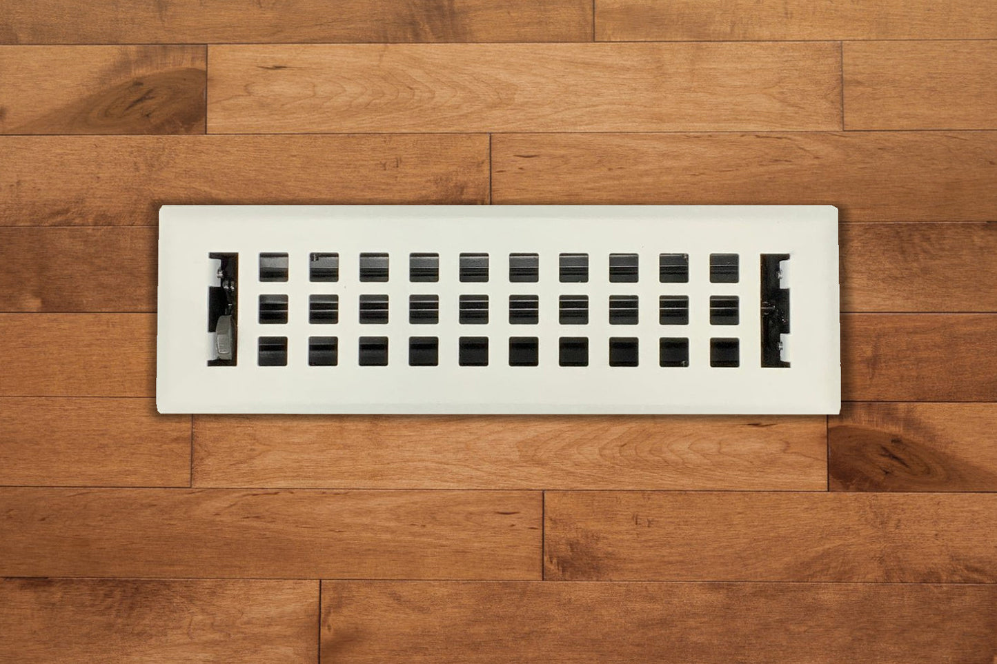 The Madelyn Carter Steel Artisan Vent Cover in white features a grid pattern and is installed in medium-toned wood flooring, adding a subtle modern touch to the space.