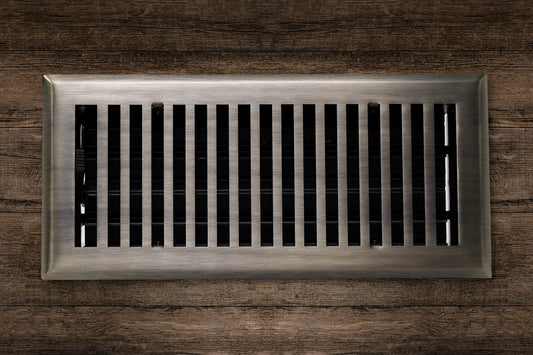 The Madelyn Carter Cast Brass Contemporary Vent Cover in Antique Brass is installed in a wooden surface, providing both functionality and modern style with its vertical metal slats.
