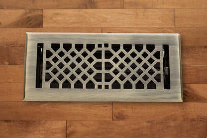 The Madelyn Carter Cast Brass Vintage Industrial Vent Cover in Antique Brass adds elegance to any wooden floor with its striking geometric pattern.