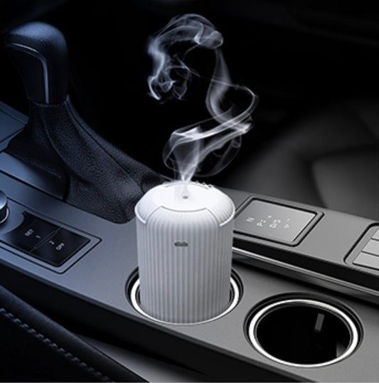 The ARO-CAR by Aromely is a small white car diffuser that uses cold air diffusion technology to emit your favorite fragrances in your car’s cup holder near the gear shift and controls.