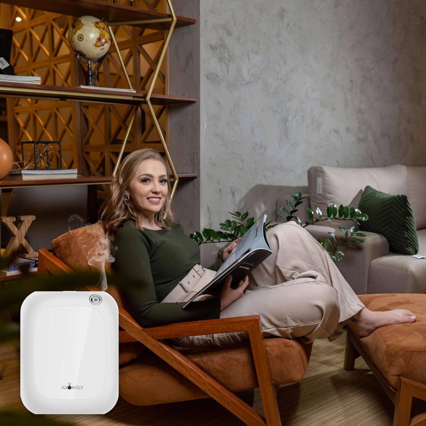 A woman relaxes in a modern living room, smiling and reading as an AROMELY Aromely Smart Bluetooth Scent Diffuser for up to 1,500 sq ft gently emits vapor nearby.