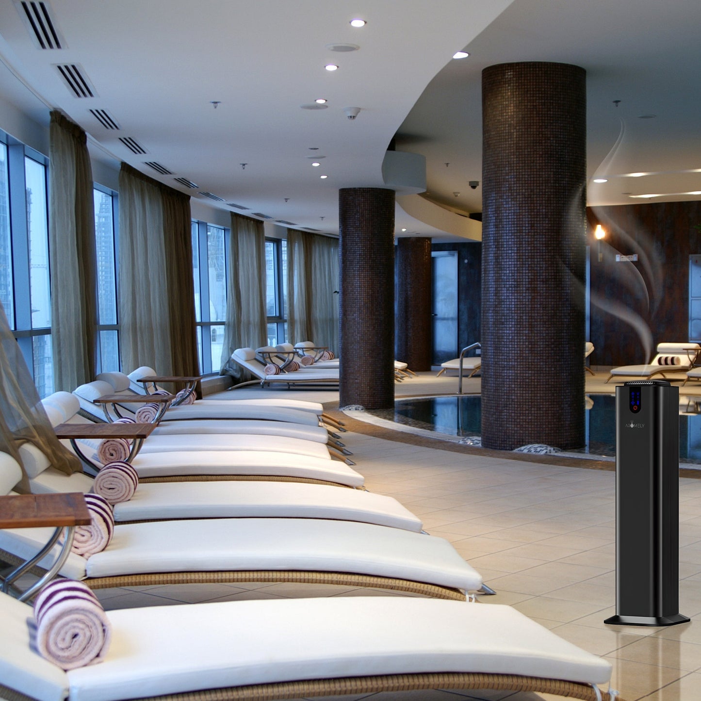 A modern indoor spa with lounge chairs, rolled towels, large windows, brown columns, a swimming pool, and the AROMELY Smart Bluetooth Scent Diffuser (up to 2,000 SQSF) by the seating area for maximum comfort.
