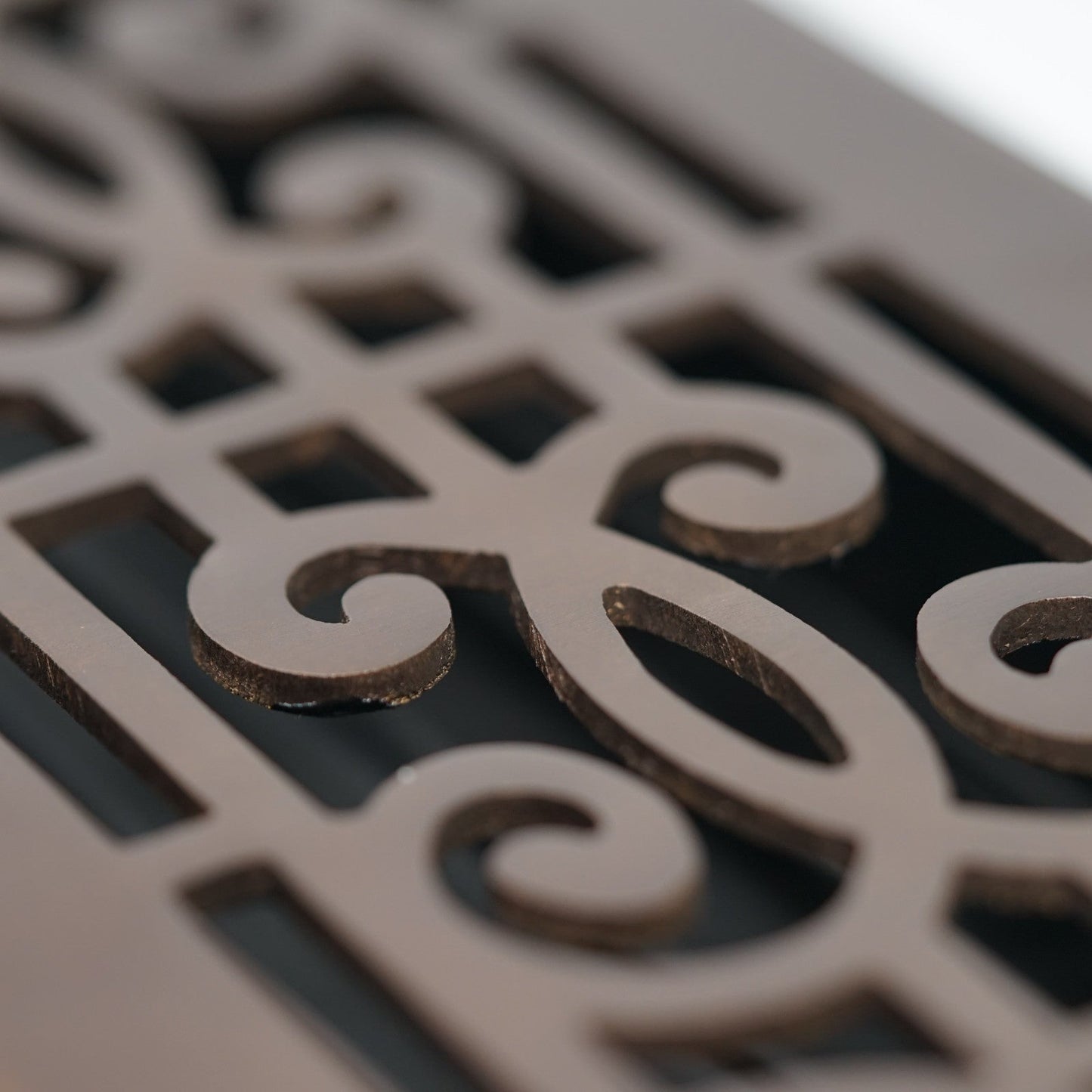 Close-up of the ornate, swirling cutout design on a Madelyn Carter Cast Brass Baroque Vent Cover in oil rubbed bronze finish, featuring rich brown tones.