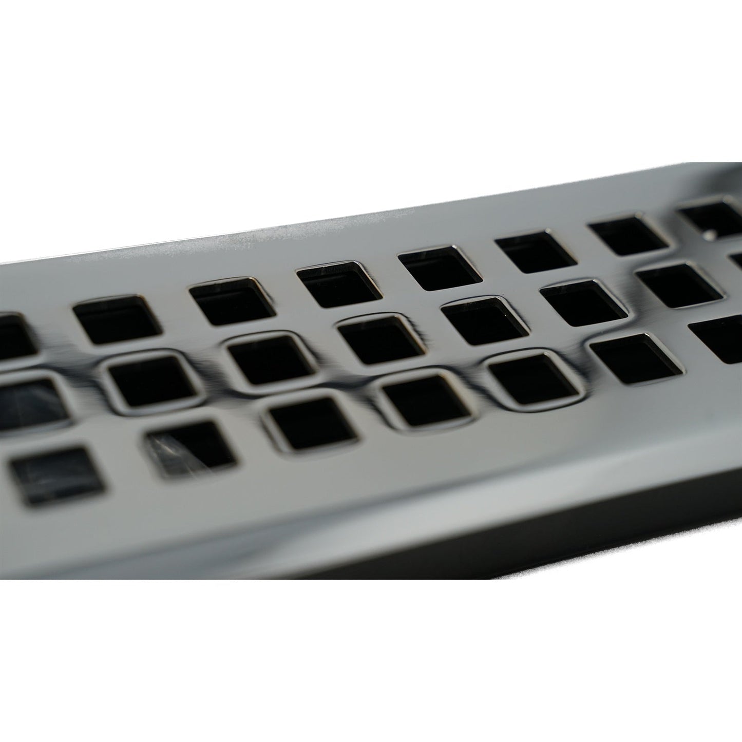 Close-up of a Madelyn Carter Cast Brass Artisan Vent Cover in Polished Chrome, featuring precision detailing and square holes arranged in rows on its metallic surface.