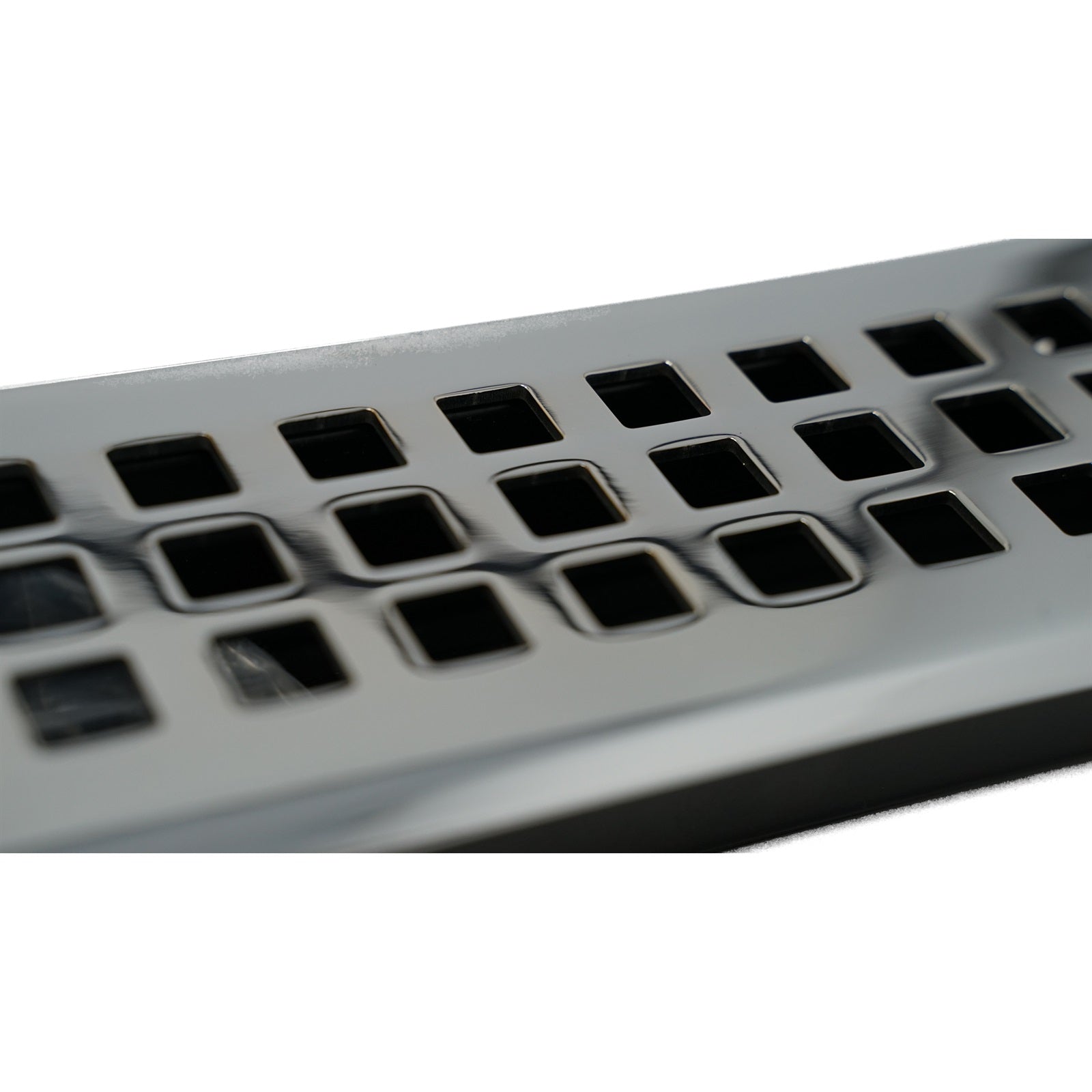 Close-up of a Madelyn Carter Cast Brass Artisan Vent Cover in Polished Chrome, featuring precision detailing and square holes arranged in rows on its metallic surface.