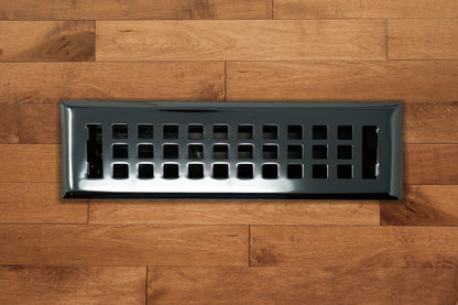 A Madelyn Carter Cast Brass Artisan Vent Cover in Polished Chrome with square openings is installed in a wooden floor with a medium brown finish.