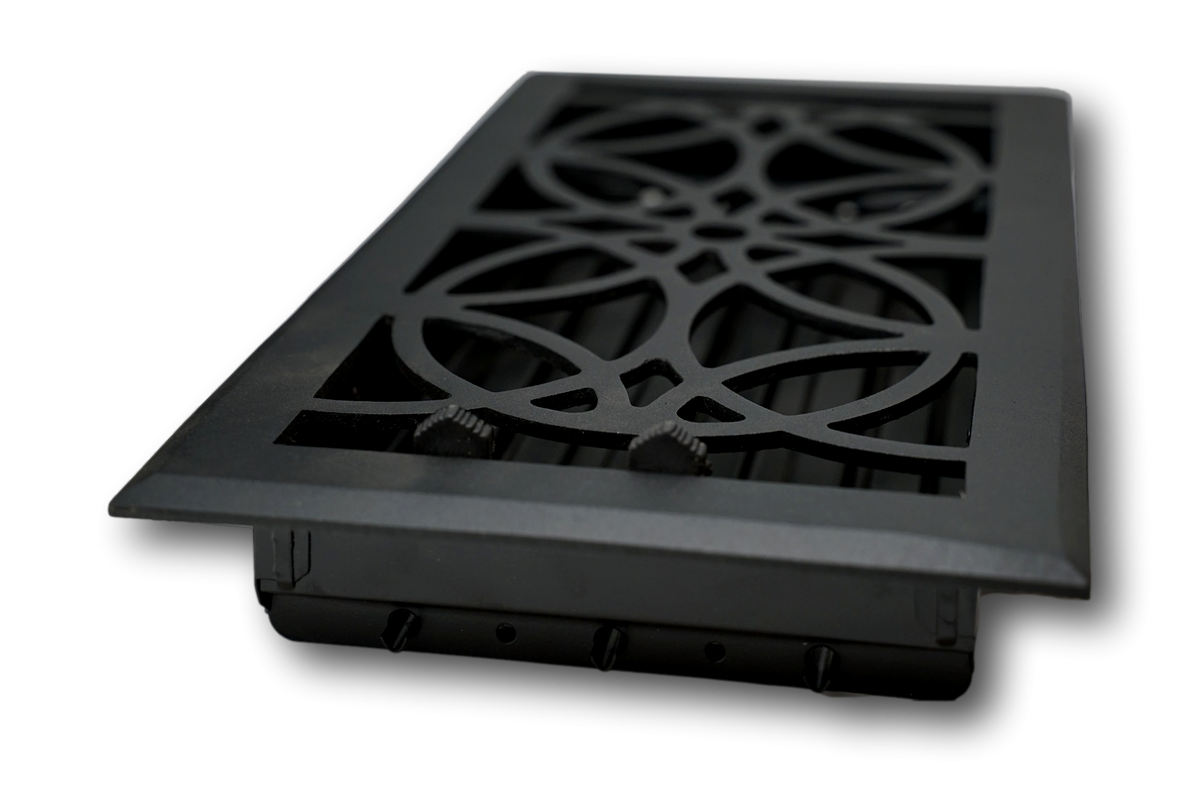 The Madelyn Carter Cast Aluminum Empire Vent Cover in black features a decorative geometric pattern. Stylish and modern, this vent cover is designed for floor or wall installation and shown angled against a white background.
