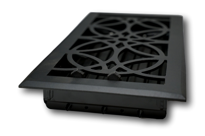 The Madelyn Carter Cast Aluminum Empire Vent Cover in black features a decorative geometric pattern. Stylish and modern, this vent cover is designed for floor or wall installation and shown angled against a white background.