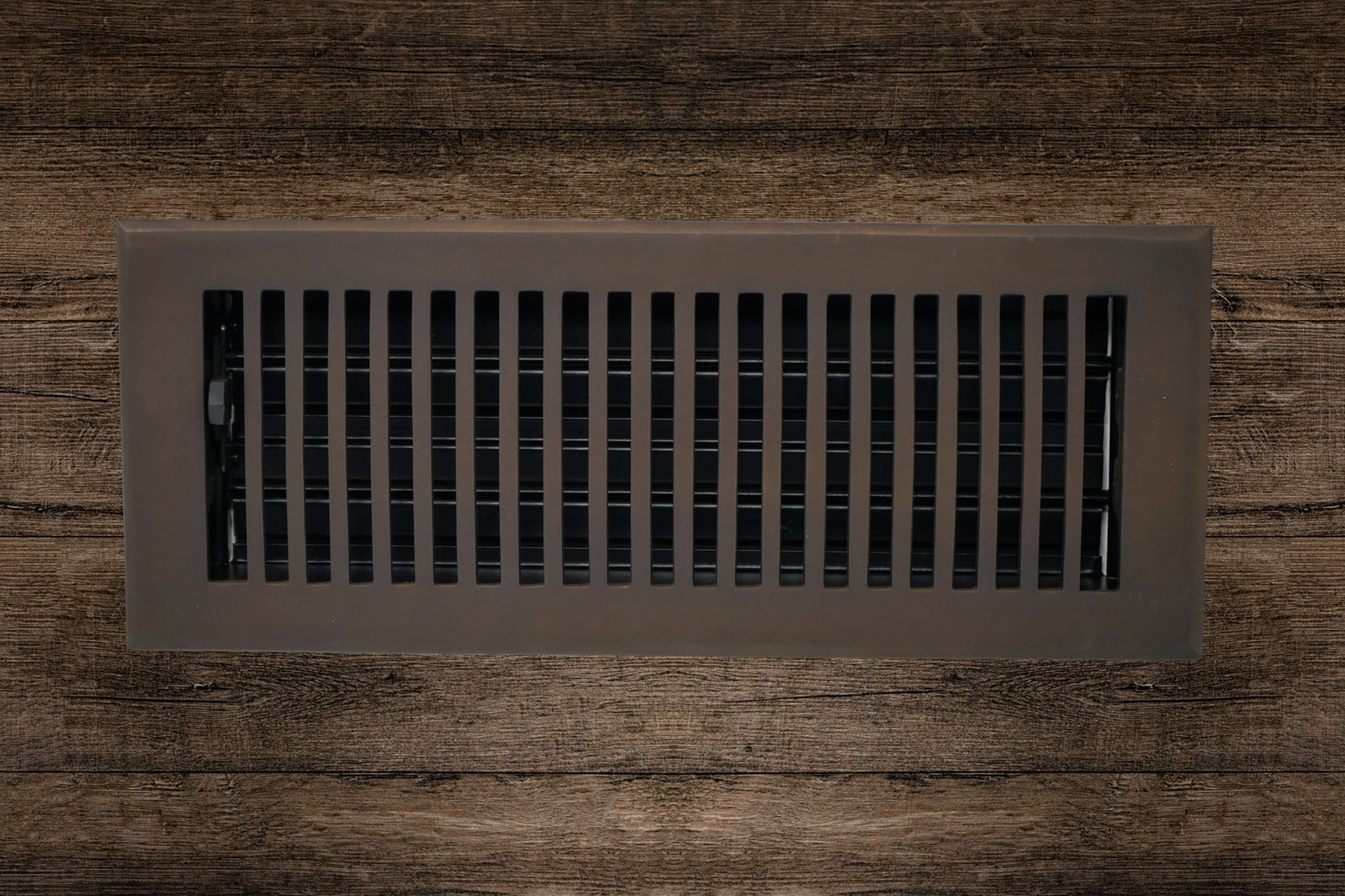 The Madelyn Carter Cast Brass Contemporary Vent Cover in Oil Rubbed Bronze features vertical slats and adds a sleek, modern touch to dark wood floors while ensuring efficient air circulation.