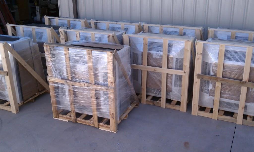 Several EP Custom Four Way Angled Face Concentric Diffusers are wrapped in plastic and secured in wooden crates, organized in rows on a concrete floor in front of a metal building.