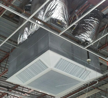 The EP Custom Four Way Angled Face Concentric Diffuser is installed in an unfinished ceiling with exposed beams and insulation, providing efficient HVAC air distribution through large industrial ductwork.