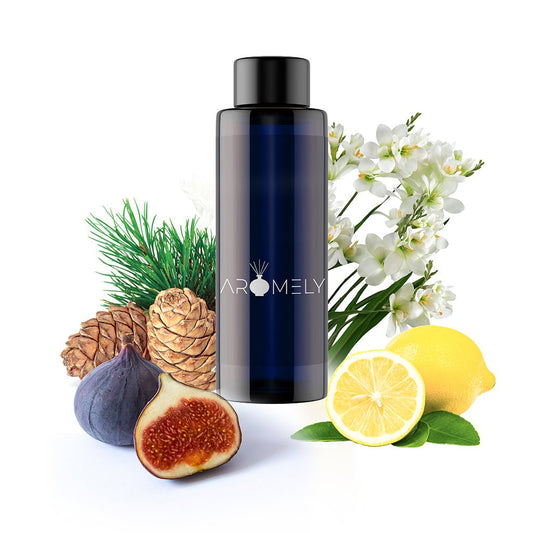 A dark blue AROMELY bottle labeled "St. Tropez - Inspired by: Edition Hotel®" is surrounded by pinecones, fig, lemon, white flowers, and pine needles on a white background.