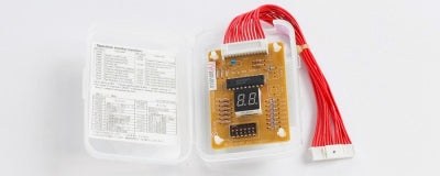 The Mitsubishi P-Series Control Service Tool, featuring a digital display and red wiring harness, is housed in a plastic case beside an instruction sheet, enabling easy self-diagnosis.