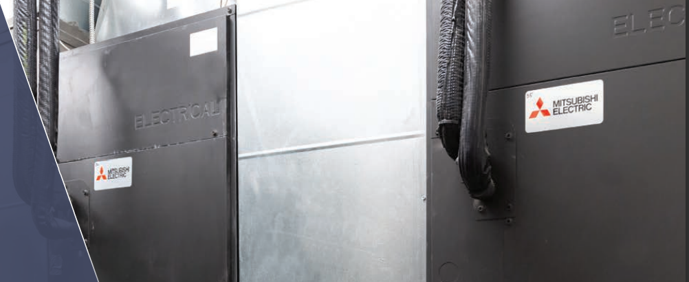 Two Mitsubishi Indoor MultiPosition Air Handler (PVA) units, known for high energy efficiency, are installed side by side in an industrial setting with metal paneling in the background.